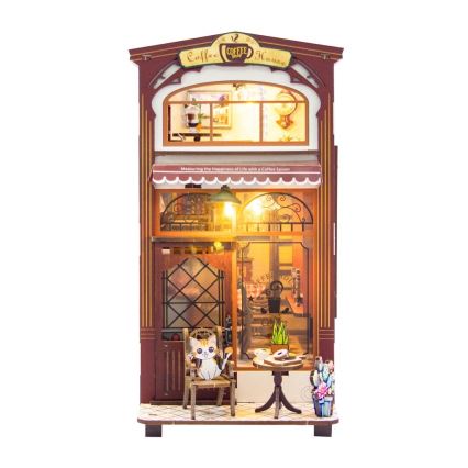 Drevená kaviarňová miniatúra zobrazuje mačku sediacej na stoličke pred kaviarňou. Kaviarňu osvetľujú svetlá. Nápis na kaviarni znie: „Coffee House“ a „Measuring the happiness of Life with a Coffee Spoon“.