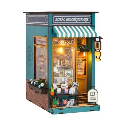 Drevená miniatúra kníhkupectva „SOUL BOOKSTORE“ s výkladmi, markízou a vonkajším predajným pultom. V oknách sú viditeľné knihy a vývesný štít uvádza otváracie hodiny (9:00 - 18:00). Na pulte je nápis „MAKE A BOOK ITS A HOOK“ a reklama „30% OFF“.