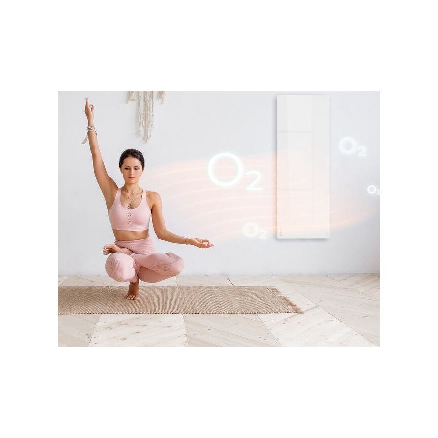 Žena v ružovom športovom oblečení medituje v sede na podlahe. Pred ňou je vysoký biely vykurovací panel, z ktorého vychádzajú svetelné prúdy s označením O₂. Podlaha je svetlá drevená.