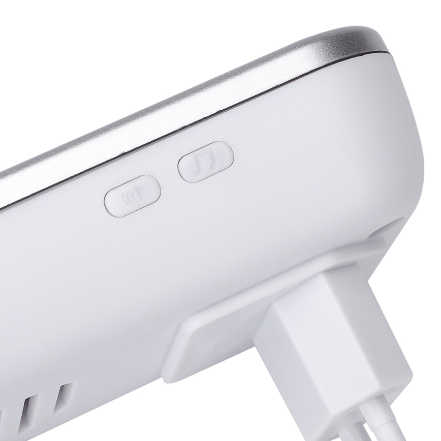 Biely bezdrôtový zvonček s dvomi tlačidlami: jedno pre zapnutie/vypnutie zvuku, druhé pre výber melódie. Je pripojený k elektrickej zásuvke.