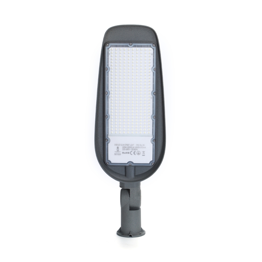 LED pouličné svietidlo s mnohými LED diódami je umiestnené na sivom stojane. Na zadnej strane svietidla je nápis: 100W LED STREET LIGHT, 220V-240V 50/60Hz IP65, 20000LM, 3000K 85-90RA, 2010050001, RoHS CE.