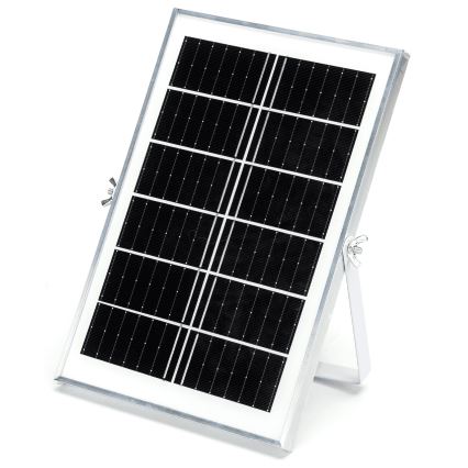 Solárny panel s tmavými článkami je umiestnený na sklopnom kovovom stojane. Panel je obdĺžnikového tvaru a je zabudovaný v bielom ráme. Celá zostava je na bielom pozadí.