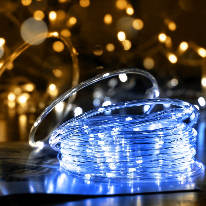 Svetelný pás s modrými LED diódami je zrolovaný na tmavom povrchu. V pozadí sú rozostrené zlaté svetielka.