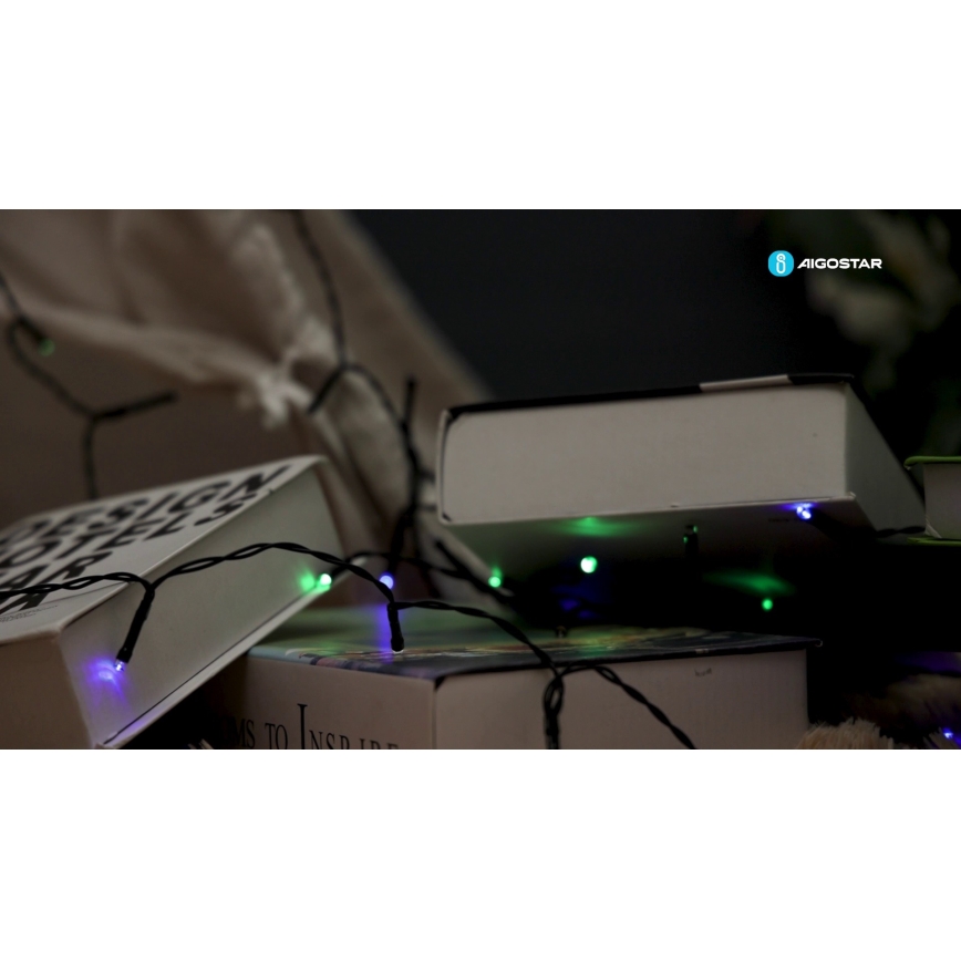 Svetlený veniec s farebnými LED diódami (fialová, zelená) leží na knihách. Knihy sú položené na sebe. Na jednej knihe je viditeľný text: „DESIGN HOTEL IDEAS“. V pravom hornom rohu je logo „AIGOSTAR“.