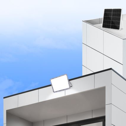 LED svetlomety sa montujú na modernú budovu. Solárny panel je umiestnený na streche vedľajšej budovy. Jasná obloha.