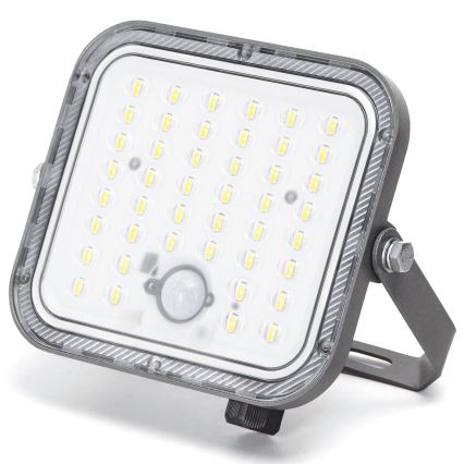 LED svetlo s pohybovým senzorom svieti. Je štvorcového tvaru, sivé, má mnoho malých LED diód. Svetlo je umiestnené na kovovom držiaku.