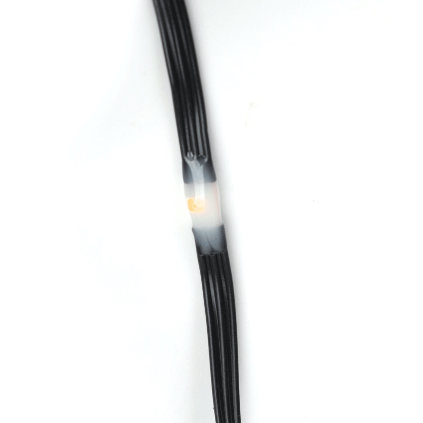 Svetlo emitujúca dióda je zalepená do čierneho kábla. Kábel je zložený z viacerých tenkých vodičov. Pozorované na bielom pozadí.
