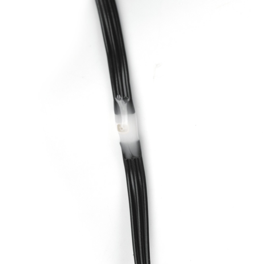 Čierny kábel s viacerými vodičmi je spojený priehľadnou zmršťovaciou bužírkou. Spojenie je umiestnené na bielom pozadí.