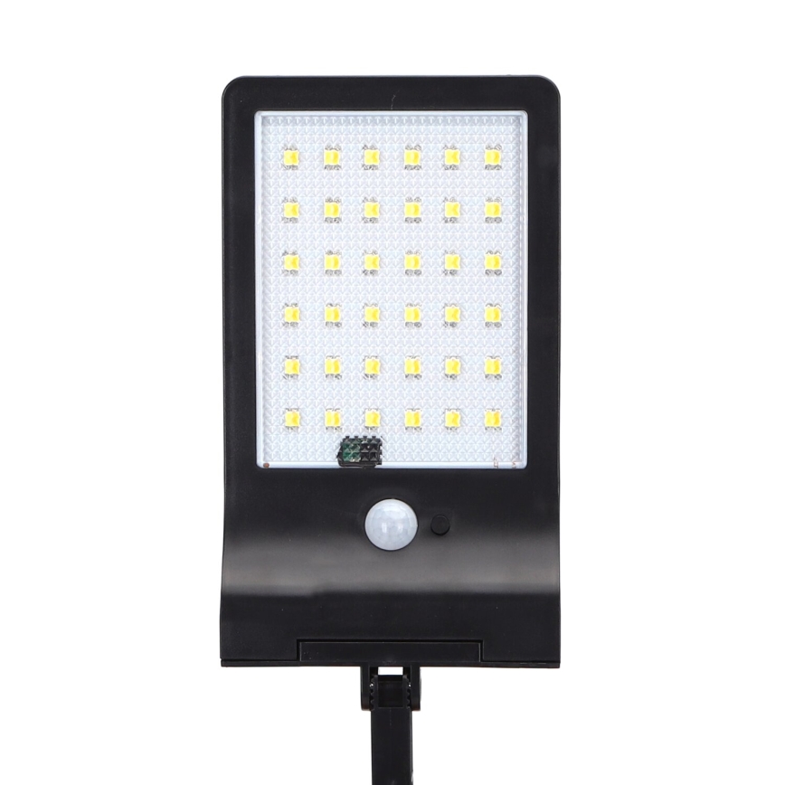 Solárny LED svietiaci panel s 36 LED diódami a pohybovým senzorom je pripevnený na čiernom stojane. Svietidlo svieti svetlom. Je umiestnené na bielom pozadí.