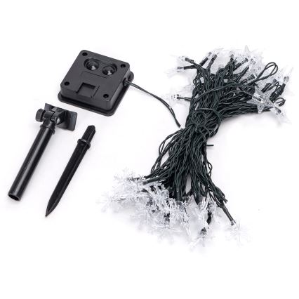 Solárny svietiaci bod s panelom na vrchu, na čiernej tyčke zapichnutej do zeme. Na kábli je štítok: GOOSTAR 20 LED SOLAR LIGHT, MODEL 2020AA, 200MA, FC/ASTER 120M, CA/LOT 240806-12, DC12V 0.08W, ONLY WET LOCATION.