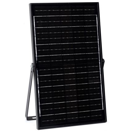 Solárny panel stojí na sklopnom stojane. Panel je čierny a mriežkový, s mnohými jednotlivými článkami. Na bielom pozadí.