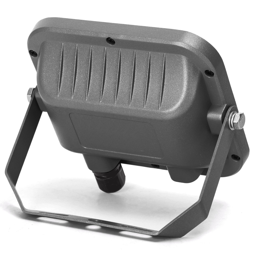 Svetlomet z kovu je umiestnený na nastaviteľnom držiaku. Je tmavosivej farby a má pripojenie na kábel. Na bielom pozadí.