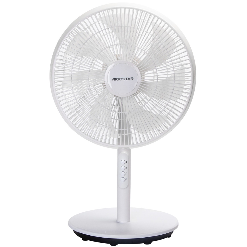 Biely stolový ventilátor značky AEGostar stojí v spálni pred posteľou. Ventilátor sa nachádza na svetlom koberci. Steny sú zelené.