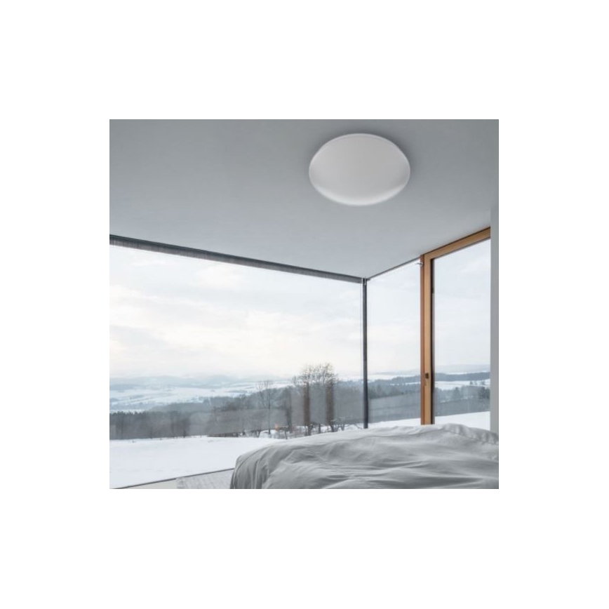 Okrúhle stropné svietidlo je umiestnené v moderne zariadenej spálni s výhľadom na zasneženú krajinu cez veľké presklené steny.