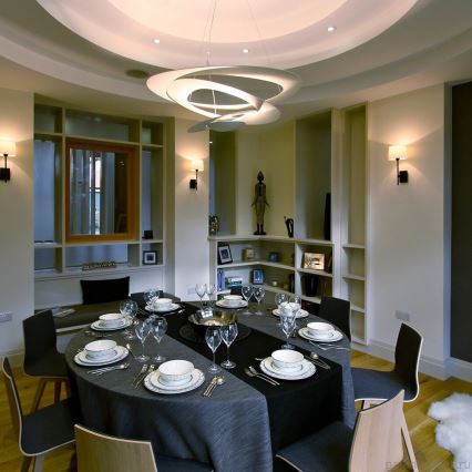 Stôl – nachádza sa na ňom prestretá tabuľa pre hostí – je v jedálni s vstavanými knižnicami a moderným osvetlením.