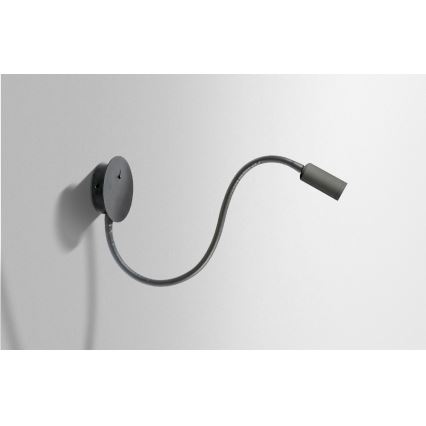 Nástenné svietidlo s ohybným ramenom je pripevnené k stene. Svietidlo smeruje doprava. Pozadie je svetlo sivá stena.