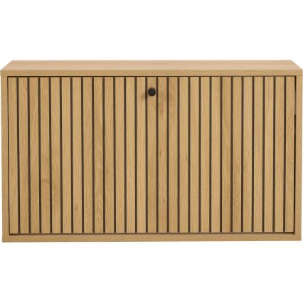 Drevená skrinka s vertikálnymi drážkami a čiernou kľučkou je zobrazená spredu. Skrinka je svetlohnedá.