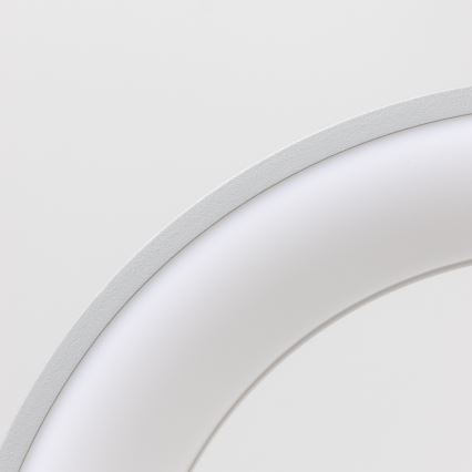 Biela oblúkovitá lampa je umiestnená na svetlom pozadí. Lampa je zapustená a má jemne textúrovaný povrch.