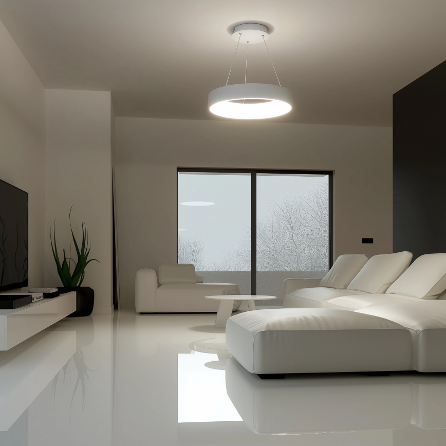 Svetlo kruhového tvaru visí zo stropu. Moderná biela sedacia súprava sa nachádza v minimalistickej obývacej izbe s veľkým oknom a lesklou podlahou.