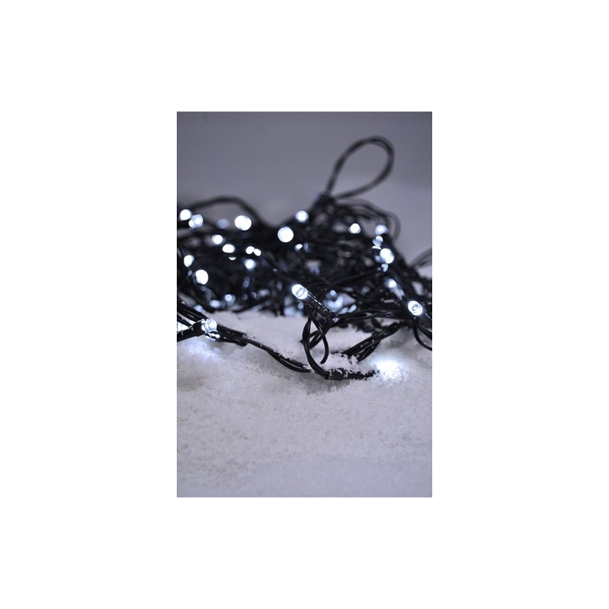 Svetelný reťaz s bielymi LED diódami na čiernom kábli leží na umelom snehu. Diódy svietia.