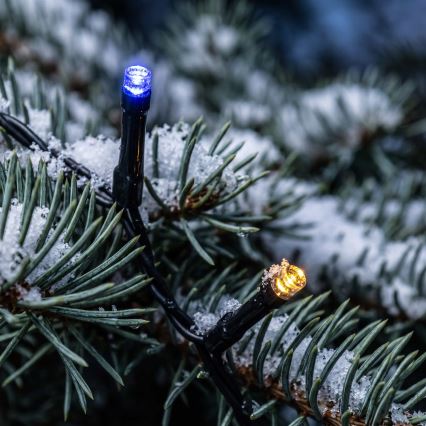 Elektrický svetelný veniec s farebnými LED diódami leží zrolovaný na svetlom povrchu. Diódy sú červené, zelené, modré a žlté.