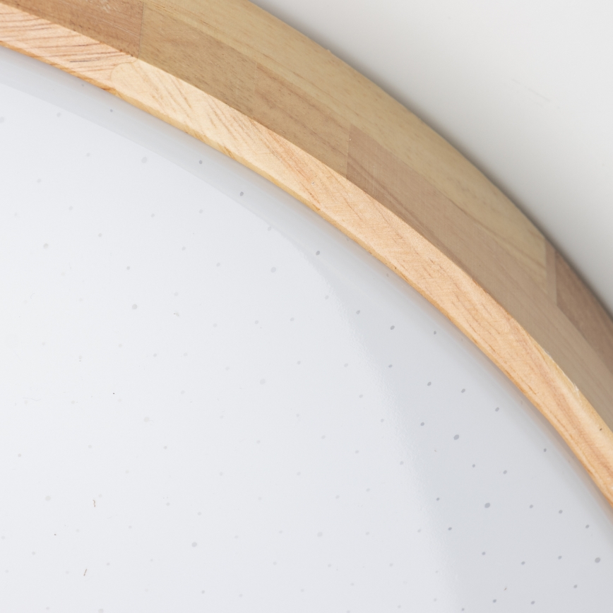 Okrúhle stropné svetlo s bielym tienidlom a dreveným rámom je pripevnené k stropu. Tienidlo je posiate drobnými bodkami.