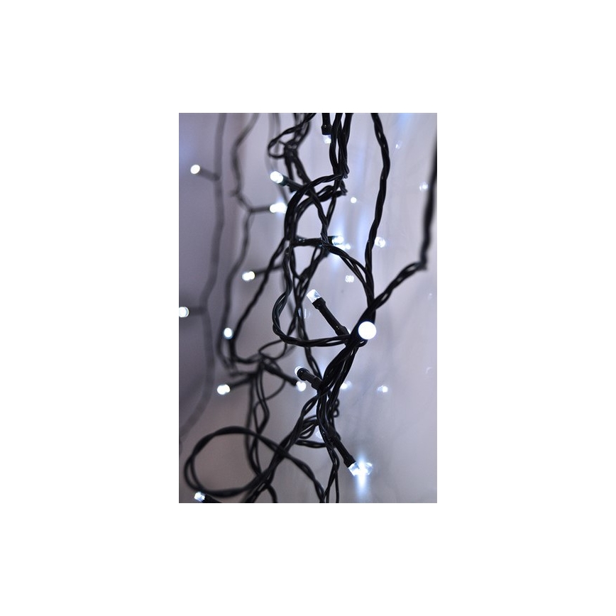 Svetelná reťaz s bielymi LED diódami na čiernych kábloch je zavesená na svetlej stene. Diódy sú rozmiestnené nepravidelne po celej dĺžke káblov.