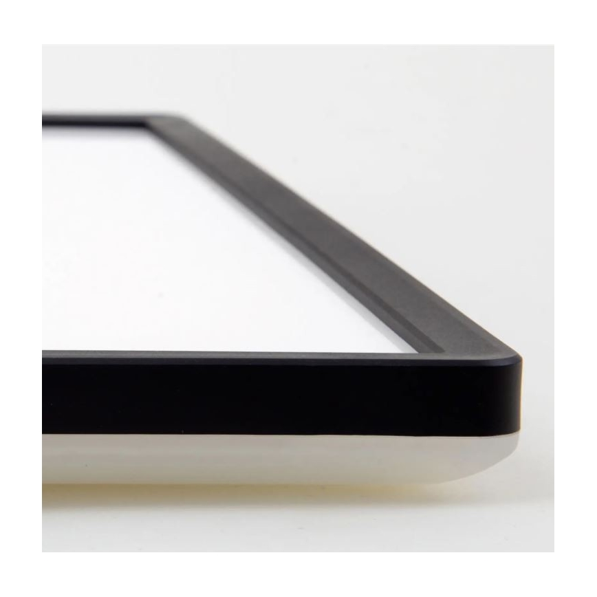 Obdĺžniková doska s bielym povrchom a čiernym rámom leží na svetlom podklade. Rám je hrubý a zreteľne viditeľný.