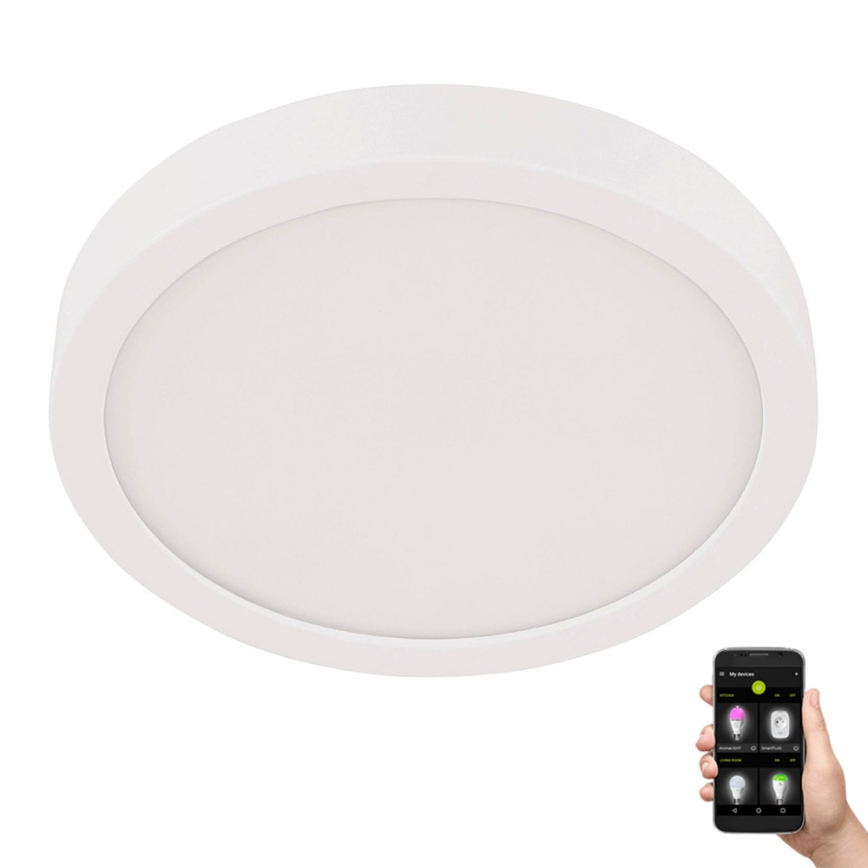 Okrúhle stropné LED svetlo svieti. Ovládanie cez mobilnú aplikáciu zobrazenú na telefóne v ruke.