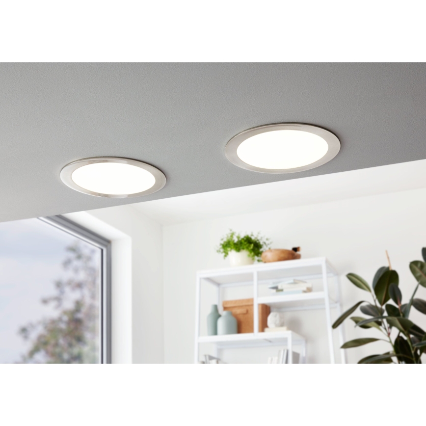 Dve kruhové LED svietidlá sú osadené na strope. Svietidlá sú zapnuté a osvetľujú priestor. V pozadí je vidieť časť miestnosti s oknom a poličkou.