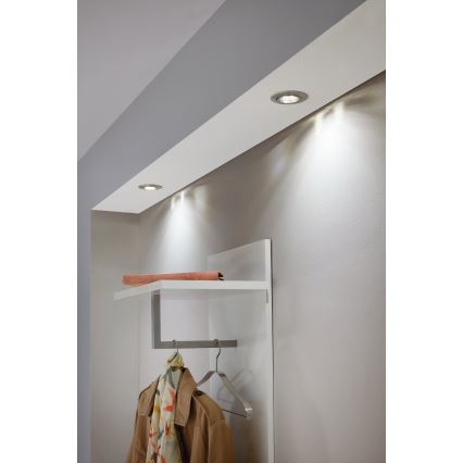 Zabudované stropné svietidlá svietia na bielu poličku s vešiakom a oblečením v chodbe.