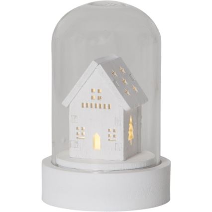 Drevený domček s LED osvetlením je umiestnený pod sklenenou kupolou na bielej podložke. Domček má vyrezávané okná a hviezdičky.