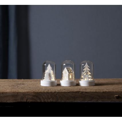 Tri malé sklené dómy s bielymi drevenými motívmi (stromčeky, domček, soby) a vnútorným LED osvetlením stoja na drevenom povrchu.