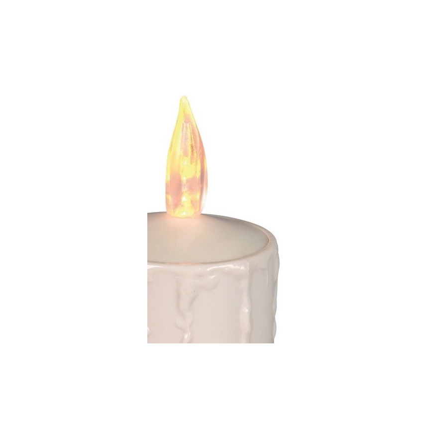 LED sviečka svieti. Je biela, s reliéfnym vzorom kvapiek vosku. Vyzerá ako čajová sviečka.