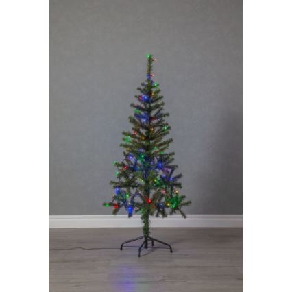 Umelý vianočný stromček s farebnými svetielkami stojí na podlahe pred sivou stenou. Stromček je osvetlený viacfarebnými LED diódami.