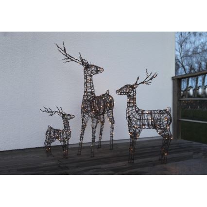 Tri kovové sochy jeleňov s integrovanými svetelnými zdrojmi stoja na terase pred domom. Najväčší jeleň je v strede, menší po jeho stranách.
