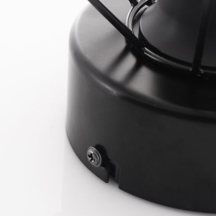 Čierna kovová základňa drží lampu. Základňa je pripevnená skrutkou. Biela plocha tvorí pozadie.