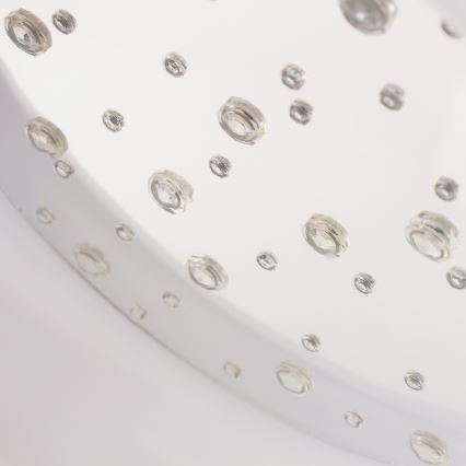 Okrúhly priesvitný objekt s malými priehľadnými výstupkami, rozmiestnenými po povrchu, je umiestnený na bielom podklade.