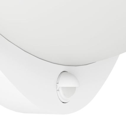 Biela nástenná lampa s integrovaným pohybovým senzorom. Senzor je umiestnený pod oválnym bielym tienidlom. Lampa je pripevnená na stenu.