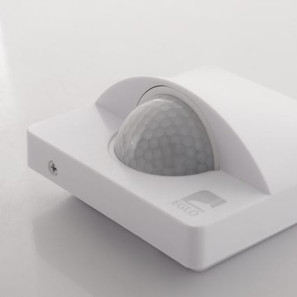 Senzor pohybu detekuje pohyb. Je zabudovaný v bielom štvorcovom puzdre s nápisom „EGLO“. Nachádza sa na svetlom povrchu.