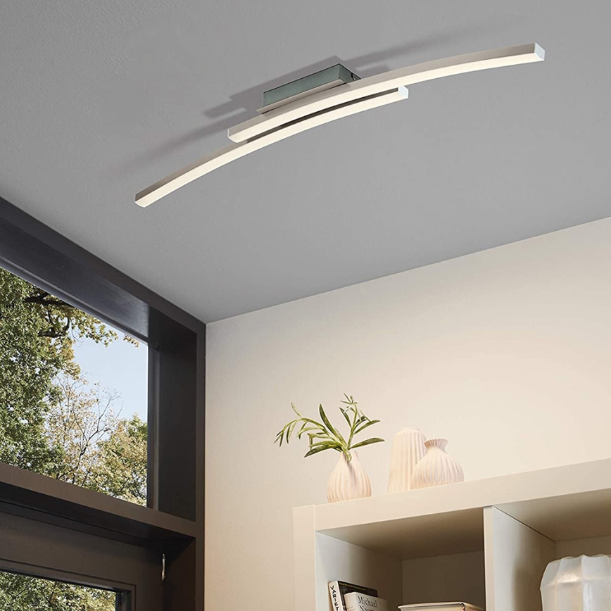 Dvojité oblúkové LED svietidlo je pripevnené k stropu. Svietidlo osvetľuje miestnosť s oknom a poličkou s kvetináčom a vázami.