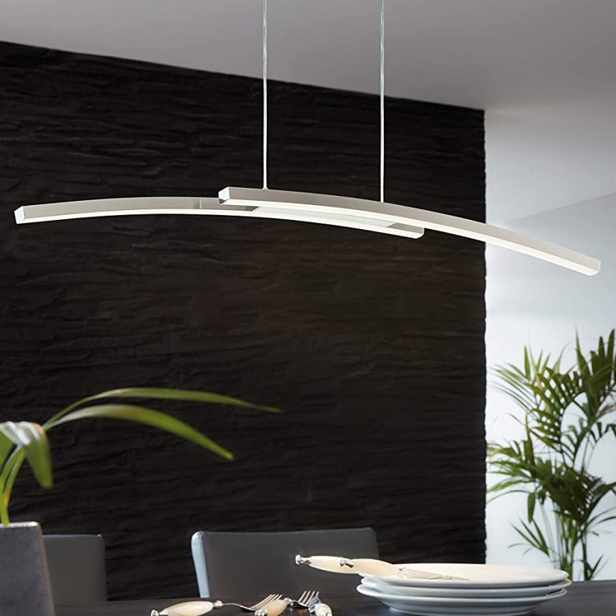 Dvojité oblúkové svietidlo visí nad jedálenským stolom. Svietidlo je strieborno-biele, s kovovou konštrukciou. Stena za stolom je tmavosivá.