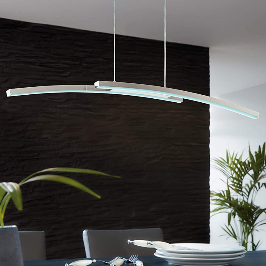 Dvojité krivočiare LED svietidlo visí nad jedálenským stolom. Svietidlo je upevnené na strope a osvetľuje tmavosivú stenu a stôl s riadom.