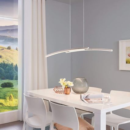 Závesné svietidlo v tvare oblúka osvetľuje jedálenský stôl v modernej jedálni s výhľadom na krajinu.