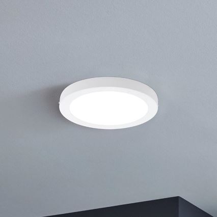 Biela kruhová LED lampa je pripevnená k sivému stropu. Lampa svieti.