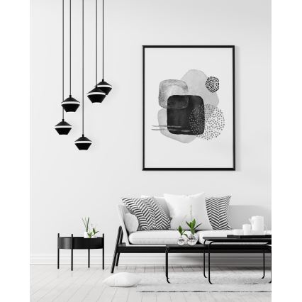 Čierne závesné lampy s tvarom obráteného kužeľa visia v minimalistickej obývacej izbe s bielym gaučom a abstraktným čierno-bielym obrazom na stene.