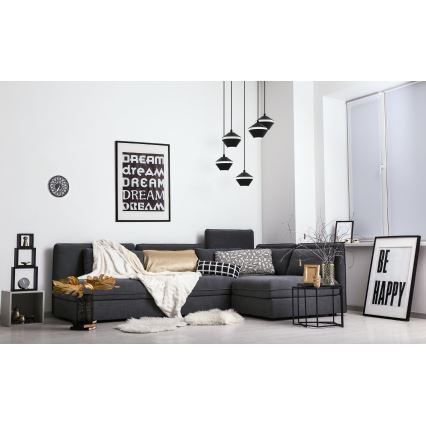 Sivá rohová sedačka stojí v obývacej izbe. Na stene visia obrazy s textom: „DREAM dream DREAM DREAM DREAM“ a „BE HAPPY“. Nad sedačkou visia tri čierne závesné lampy.