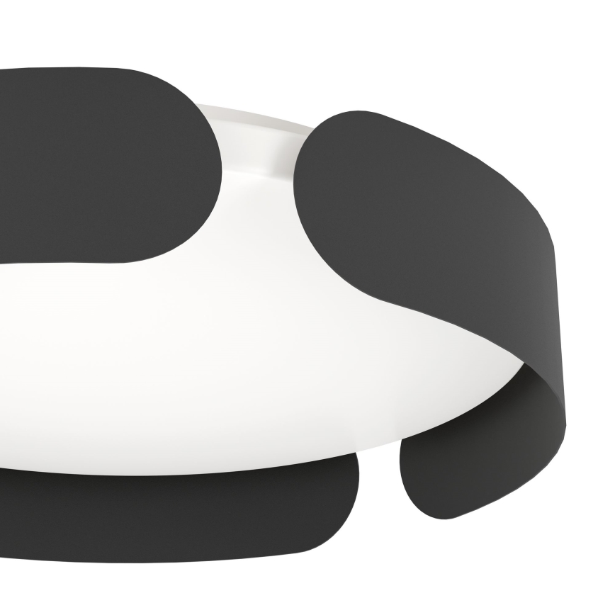 Svietidlo s bielym difúzorom je obklopené tmavosivými, organicky tvarovanými prvkami. Svietidlo je umiestnené v bielom pozadí.