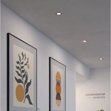 Dva obrazy s abstraktnou grafikou visia na stene chodby. Na strope sú zabudované bodové svetlá. Na stene je nápis: „CONTEMPORARY ART ← EXHIBITION“.