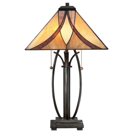 Stolová lampa s trojuholníkovým tienidlom zo skla s hnedými a béžovými odtieňmi stojí na kovovom podstavci s oblými ozdobnými prvkami. Lampa má dekoratívne retiazky s guličkami.